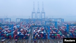 FILE - Containers and trucks are seen on a snowy day at an automated container terminal in Qingdao port, Shandong province, China, Dec. 10, 2018, 