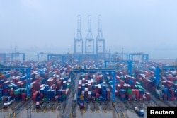 FILE - Containers and trucks are seen at an automated container terminal in Qingdao port, Shandong province, China, Dec. 10, 2018.