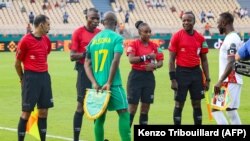 Les arbitres s'entretiennent avec les capitaines d'équipe pendant le match entre le Zimbabwe et la Guinée au Stade Ahmadou Ahidjo à Yaoundé, le 18 janvier 2022.