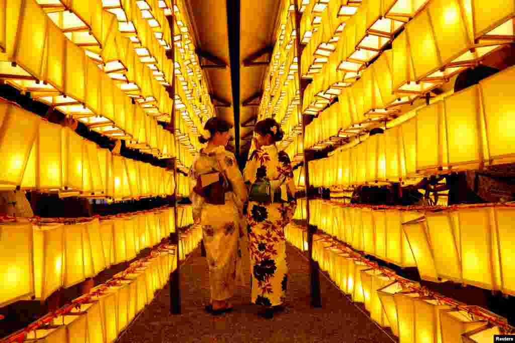 Women in yukatas, or summer-style kimonos, pose to take their photos between paper lanterns during the annual Mitama Festival at the Yasukuni Shrine, where more than 2.4 million war dead are enshrined, in Tokyo, Japan.