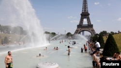 Парижани і туристи у фонтанах Трокадеро біля Ейфелевої вежі у столиці Франції 25 червня 2019 р.