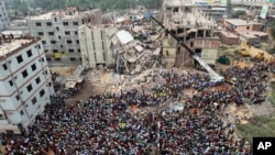 FILE - In this April 25, 2013, photo, people gather as rescuers look for survivors and victims at the site of a building that collapsed a day earlier, in Savar, near Dhaka, Bangladesh. The building housed five garment factories.