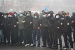 哈萨克斯坦的抗议民众在阿拉木图手挽手站在防暴警察前。（2022年1月5日）