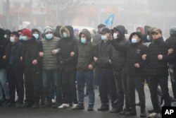 哈萨克斯坦的抗议民众在阿拉木图手挽手站在防暴警察前。（2022年1月5日）