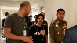 El jefe de la Policía de Inmigración, mayor general Surachate Hakparn, camina con la joven saudí Rahaf Mohammed Alqunun antes de salir del aeropuerto de Suvarnabhumi en Bangkok, Tailandia, el 7 de enero de 2019.