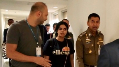 El jefe de la Policía de Inmigración, mayor general Surachate Hakparn, camina con la joven saudí Rahaf Mohammed Alqunun antes de salir del aeropuerto de Suvarnabhumi en Bangkok, Tailandia, el 7 de enero de 2019.