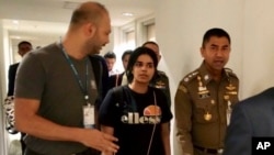 In this photo released by the Immigration Police, Chief of Immigration Police Maj. Gen. Surachate Hakparn, right, walks with Saudi woman Rahaf Mohammed Alqunun before leaving the Suvarnabhumi Airport in Bangkok, Thailand, Jan. 7, 2019.
