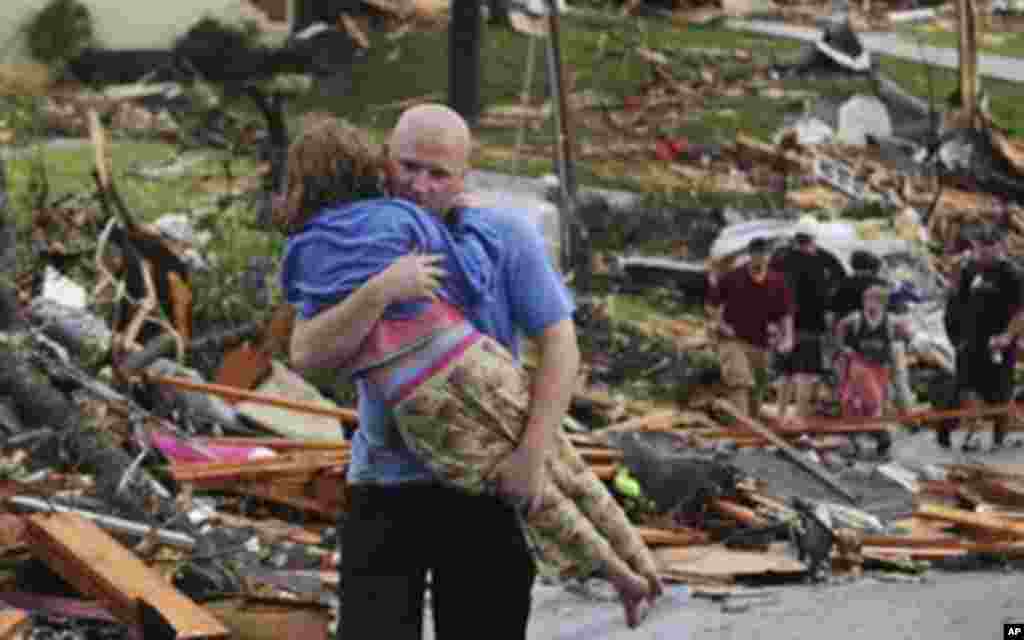 A man carries a young girl who was rescued after being trapped with her mother in their home after a tornado hit Joplin, Mo. on Sunday evening, May 22, 2011. The tornado tore a path a mile wide and four miles long destroying homes and businesses. (AP Phot