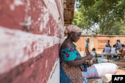 FILE - A vendor waits for customers to exchange her goods for other goods at the barter market in Togoville, Nov. 24, 2018.