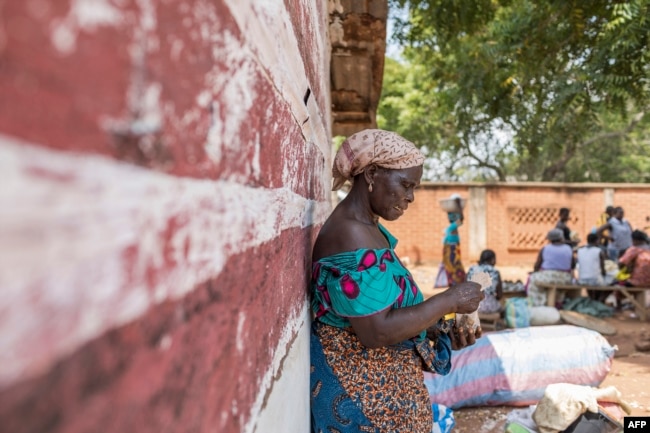 FILE - A vendor waits for customers to exchange her goods for other goods at the barter market in Togoville, Nov. 24, 2018.