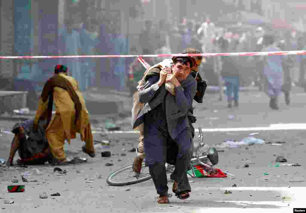 A man caries a wounded person to the hospital after a blast in Jalalabad, Afghanistan, Aug. 19, 2019.