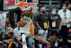 Milwaukee Bucks forward Giannis Antetokounmpo, top, dunks over Phoenix Suns guard Chris Paul during the second half of Game 5 of basketball's NBA Finals, Saturday, July 17, 2021, in Phoenix. (AP Photo/Ross D. Franklin)