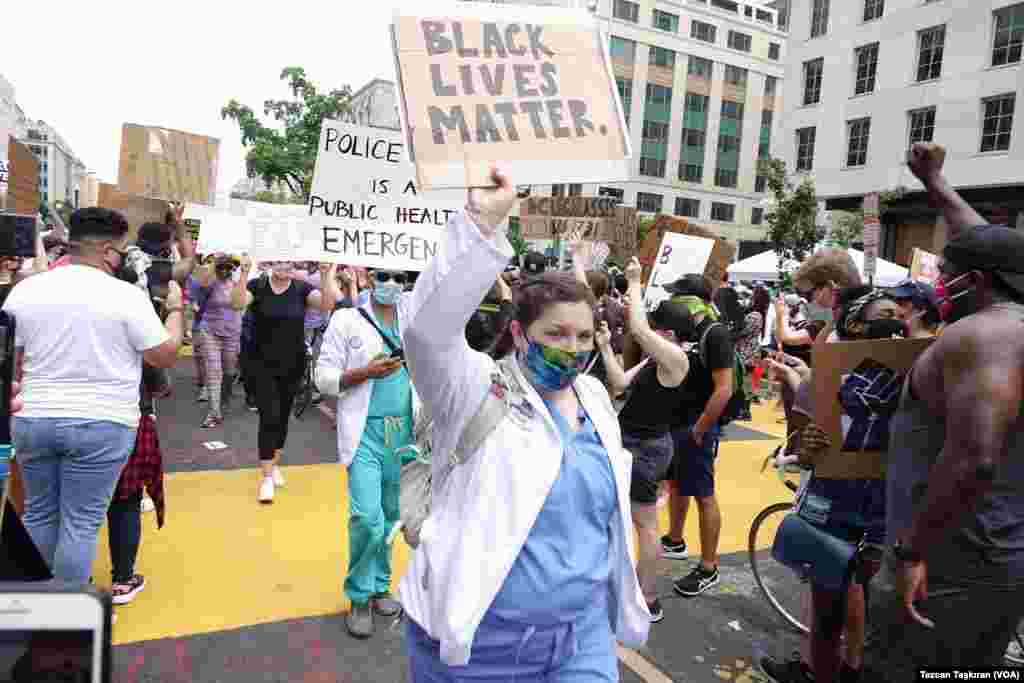 Gösterilere katılan sağlık çalışanlarından biri &#39;Polis şiddeti bir sağlık krizidir&#39; yazılı pankart taşıyor