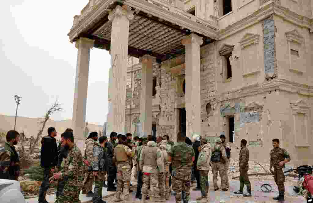 Tentara pemerintah Suriah berkumpul di luar istana yang rusak di Palmyra, Suriah tengah.