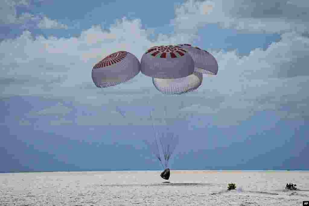 In this image taken provided by SpaceX, a capsule carrying four people parachutes into the Atlantic Ocean off the Florida coast, Sept. 18, 2021. The all-amateur crew was the first to circle the world without a professional astronaut.