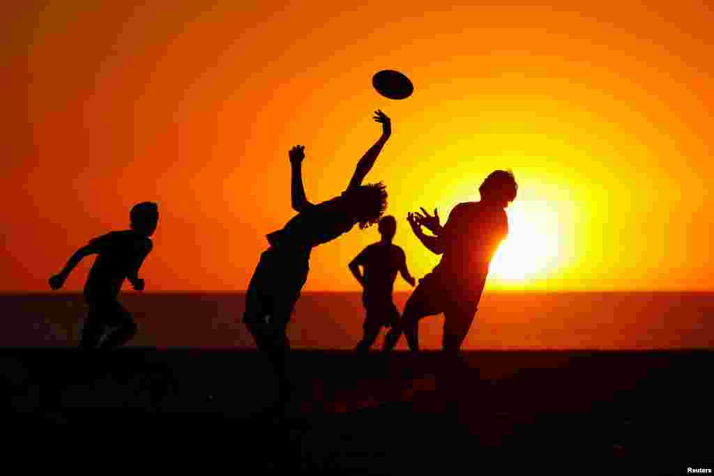 A group of boys plays sports on the sand as the sun sets at Moonlight beach in Encinitas, California, Oct. 16, 2018.