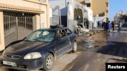 Civilians and security personnel stand at the scene of an explosion at a police station in the Libyan capital Tripoli, March 12, 2015.