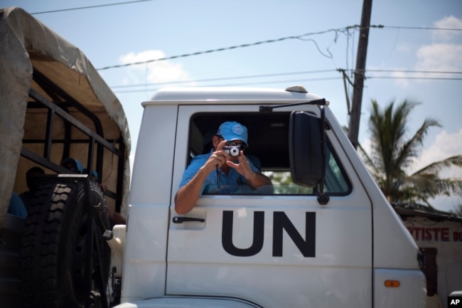 FILE - A member of U.N. peacekeepers takes a picture of demonstrators during a protest against the United Nations peacekeeping mission in Port-au-Prince, Haiti, March 22, 2013.