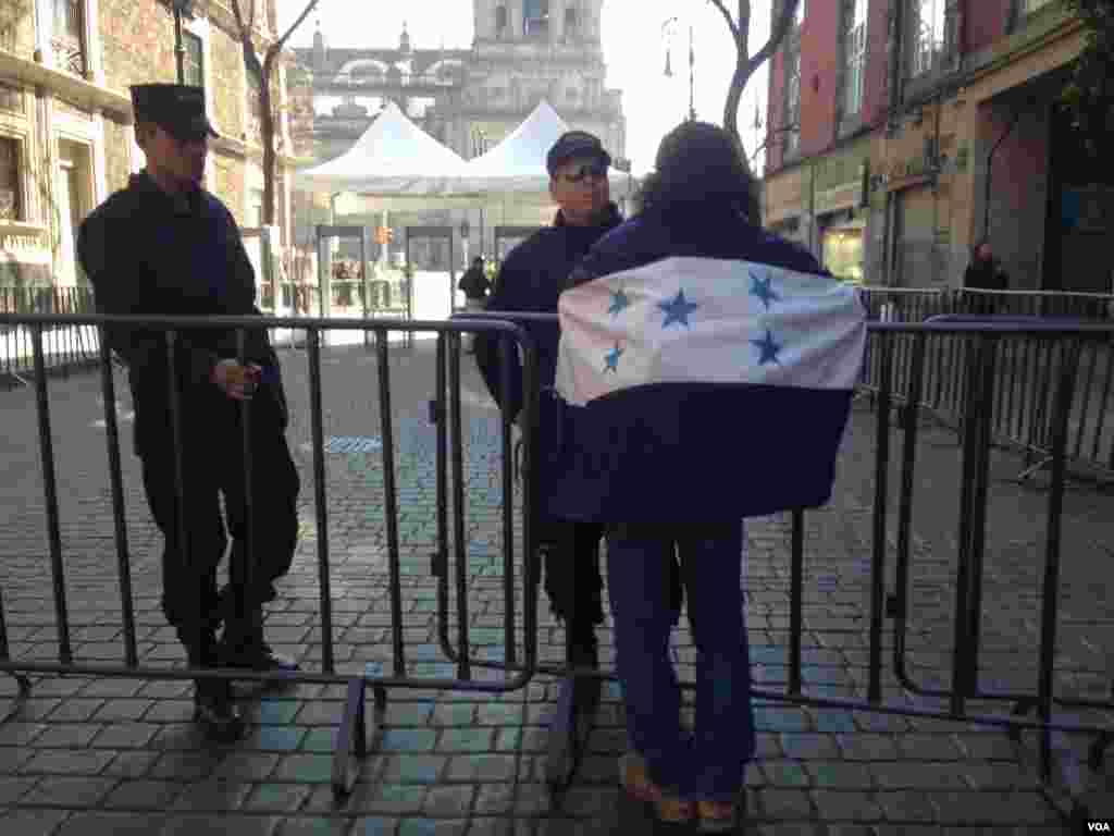 A woman with a Honduran flag draped over her shoulders talks to security personnel. (C. Mendoza/VOA) 