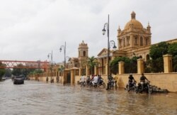 Pengendara sepeda motor lewat trotoar untuk menghindari jalanan yang tergenang banjir di depan Kampus Dayaram Jethamal Science yang dibangun pada masa kolonial Inggris, 27 Agustus 2020.