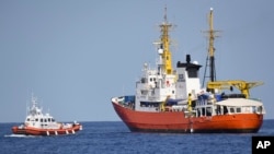 An Italian Coast Guard boat, left, approaches the French NGO "SOS Mediterranee" Aquarius ship, in the Mediterranean Sea, June 12, 2018. Italy dispatched two ships Tuesday to help take 629 migrants stuck off its shores on the days-long voyage to Spain.