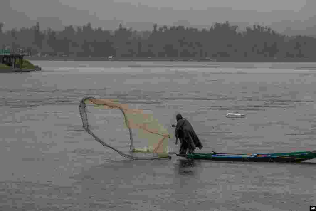 A Kashmiri fisherman throws his net into the water as it rains at the Dal Lake in Srinagar, Indian-controlled Kashmir.