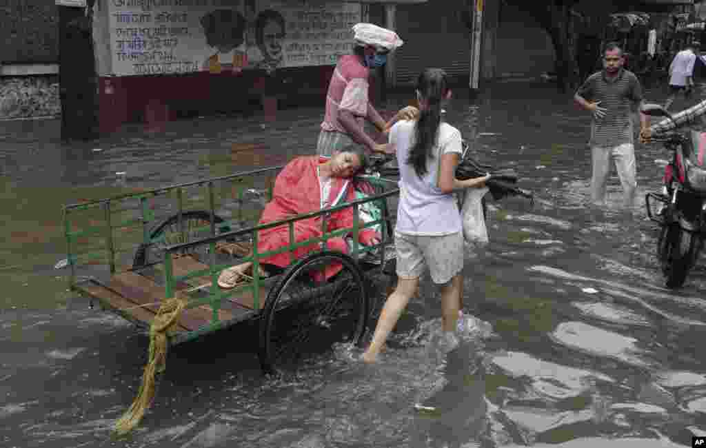 A sick person is taken on a cycle cart to a doctor in a waterlogged street following heavy rains in Kolkata, India.