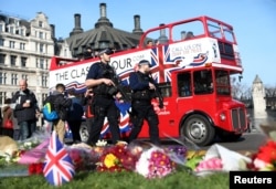 Armed police officers pass tributes in Parliament Square following a recent attack in Westminster, London, Britain, March 24, 2017.