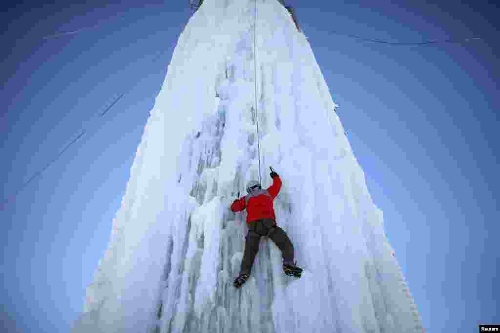 Seorang pemanjat menuruni lumbung yang ditutupi es di Cedar Falls, Iowa, AS, 17 Januari 2016.