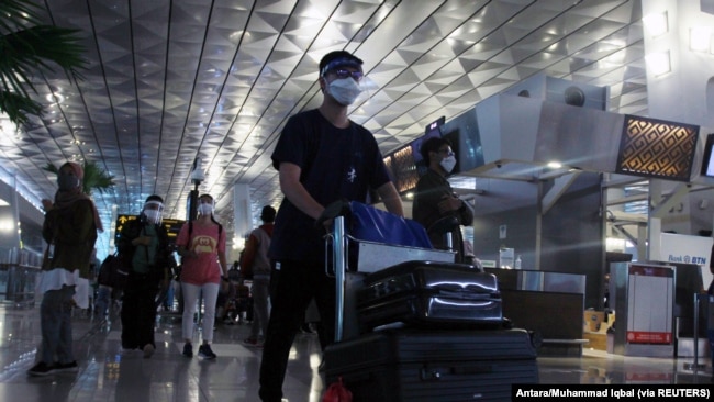 Penumpang yang memakai masker pelindung wajah berjalan di Bandara Soekarno-Hatta di tengah pandemi Covid-19, di Tangerang, 23 Desember 2020. (Foto: Antara/Muhammad Iqbal via Reuters)