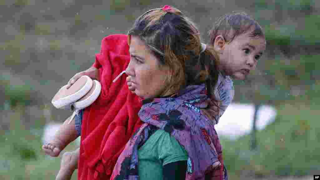 Une migrante porte un enfant à leur arrivée à la frontière austro-hongroise à Nickelsdorf, Autiche, 5 septembre 2015