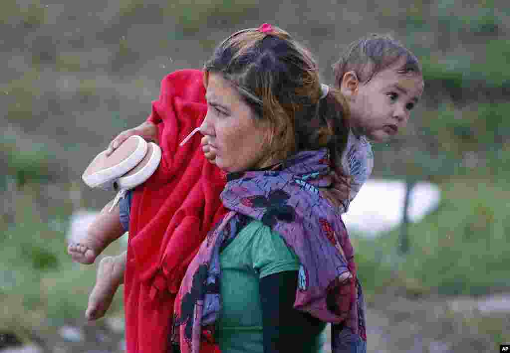 A migrants carries a child as they arrive at the Hungarian-Austrian border in Nickelsdorf, Austria, Saturday, Sept. 5, 2015, where they came from Budapest as Austria in the early-morning hours said it and Germany would let them in.