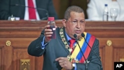 Venezuela's President Hugo Chavez holds a crude oil sample as he deliver his annual state of the nation at the National Assembly in Caracas January 13, 2012.