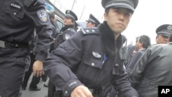A policeman tries to stop media from taking photos during the arrest of a man, after calls for a "Jasmine Revolution" protest, organized through the internet, in front of the Peace Cinema in downtown Shanghai, February 27, 2011
