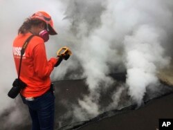 This photo provided by the U.S. Geological Survey shows a Hawaii Volcano Observatory geologist recording a temperature of 103 degrees C (218 degrees F) at a crack along Nohea Street in Leilani Estates near the town of Pahoa, Hawaii, May 9, 2018.