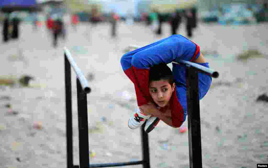 Palestinian boy Mohamad al-Sheikh, 12, who is nicknamed &#39;Spiderman&#39; and hopes to break the Guinness world records with his bizarre feats of contortion, demonstrates acrobatics skills on a beach in Gaza City on June 2, 2016.