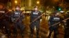 Police with wooden sticks stand guard after they cleared a group of protesters out who had stopped traffic in downtown Seattle during a demonstration against the decisions not to indict police officers who who killed men in Ferguson, Missouri and New York