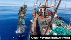 FILE - Garbage, much of it plastic, from the Great Pacific Garbage Patch between California and Hawaii is being lifted onto a cargo sailing ship by the Ocean Voyages Institute, which works to clean up trash in the ocean. 