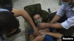 A man, affected by what activists say is nerve gas, breathes through an oxygen mask in the Damascus suburbs of Jesreen, Aug. 21, 2013. 
