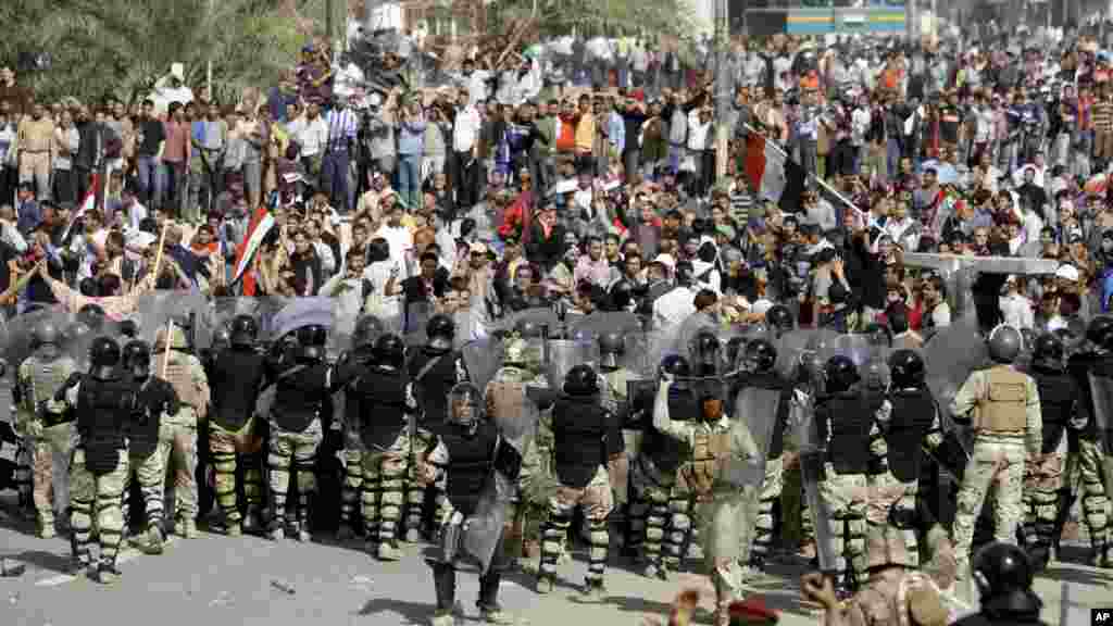 Des policiers anti-émeutes irakiens barrent la route aux manifestants anti-gouvernementaux de pénétrer dans la Zone verte fortement gardée pendant une manifestation à Bagdad, en Irak, 25 février 2011.