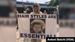 Una mujer sostiene un cartel con el lema "Los peinados también son esenciales" durante una protesta en Miami para pedir la reapertura de Florida durante la pandemia del coronavirus.