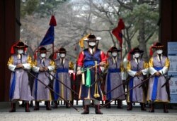 韩国首尔德寿宫前身穿传统民族服装进行表演的工作人员为防范新冠病毒戴起了口罩。（2020年1月31日）