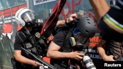 FILE - A Turkish riot policeman pushes a photographer during a protest at Taksim Square in Istanbul, June 11, 2013.