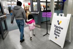 FILE - An information sign is displayed as a child arrives with her parent to receive the Pfizer COVID-19 vaccine at London Middle School in Wheeling, Ill., Nov. 17, 2021.