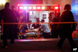 Emergency responders administer CPR to an unknown patient on a stretcher as law enforcement officials stand nearby at the emergency receiving area of Baylor University Medical Center, early Friday, July 8, 2016.