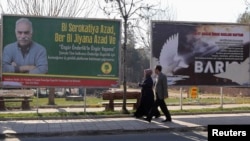 FILE - Pedestrians pass by a billboard with a picture of imprisoned Kurdish rebel leader Abdullah Ocalan in Diyarbakir, Feb. 11, 2014. 
