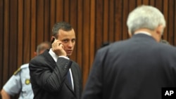 Oscar Pistorius talks on a mobile phone while waiting for proceedings to get under way in court in Pretoria, South Africa, March 24, 2014.