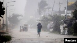 A man walks on a street while strong winds and heavy rain, brought by typhoon Hagupit, batter Atimonan town, Quezon province, south of Manila, December 8, 2014.