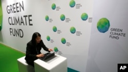 A woman works her computer at the Green Climate Fund stand at the COP21, United Nations Climate Change Conference, in Le Bourget, north of Paris, Nov. 30, 2015.