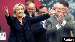 FILE - France's far right National Front political party leader Marine Le Pen (L) gestures at supporters.